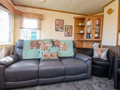 A living room with a sofa and decorative cushions at Caravan at Argraig in Llanrhyddlad near Cemaes Bay