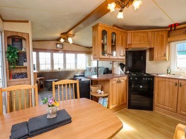 A kitchen with wooden cabinets and a table at Caravan at Argraig Llanrhyddlad near Cemaes Bay