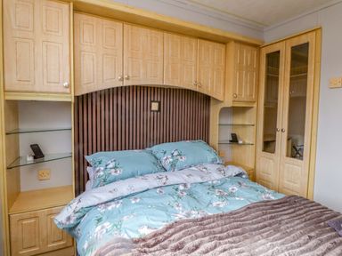 A bedroom with a bed and storage cabinets at Caravan at Argraig Llanrhyddlad near Cemaes Bay