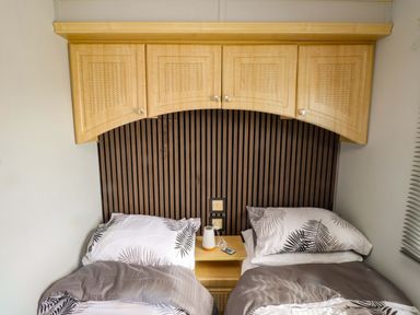 A bedroom with two beds and a nightstand at Caravan at Argraig Llanrhyddlad near Cemaes Bay