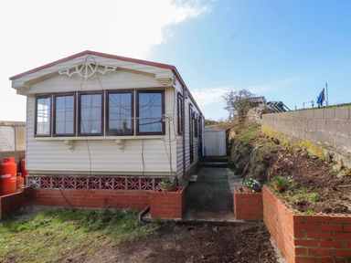 A caravan with a pathway and planter at Caravan at Argraig Llanrhyddlad near Cemaes Bay