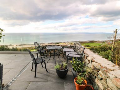An outdoor seating area with chairs and a table overlooking the sea at Briar Bank in Barmouth