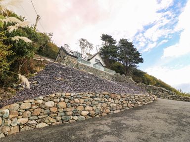 A house with a stone wall and driveway at Briar Bank in Barmouth