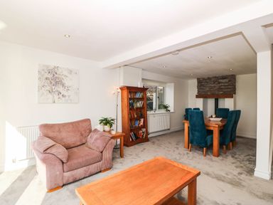 A living room with a sofa and dining area at Briar Bank in Barmouth