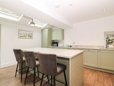 A kitchen with a large island and bar stools at Briar Bank in Barmouth