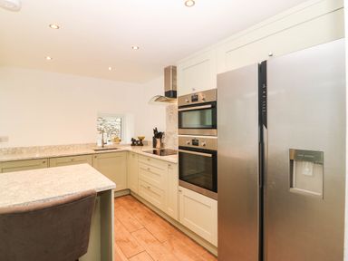 A kitchen with cabinets, oven and refrigerator at Briar Bank in Barmouth