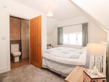 A bedroom with a bed and a door leading to a bathroom at Briar Bank in Barmouth