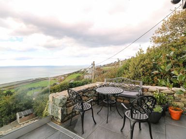 An outdoor seating area with a table and chairs overlooking the coast at Briar Bank in Barmouth
