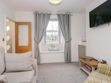 A living room with a window and sofa at Bobtail Cottage in Kendal