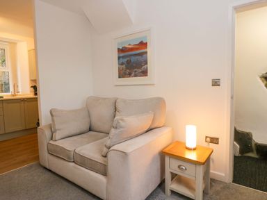 A living room with a sofa and lamp at Bobtail Cottage in Kendal