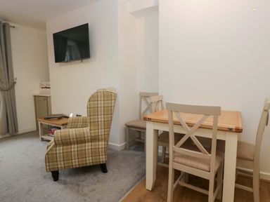 A living room with an armchair and dining table at Bobtail Cottage in Kendal