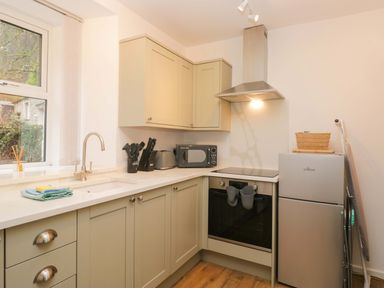 A kitchen with cabinets, sink, refrigerator, and microwave at Bobtail Cottage in Kendal