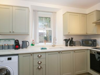A kitchen with cabinets and appliances at Bobtail Cottage in Kendal