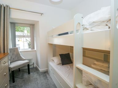 A bedroom with a bunk bed and chair at Bobtail Cottage in Kendal