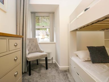 A bedroom with a bunk bed and a chair at Bobtail Cottage in Kendal