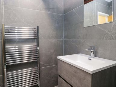 A bathroom with a sink and towel radiator at Bobtail Cottage in Kendal