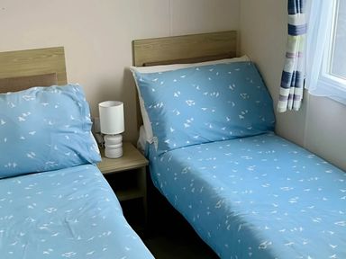 A bedroom with two beds and a bedside lamp at Static Caravan Hoburne Devon Bay in Paignton