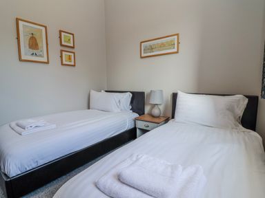 A bedroom with twin beds and a bedside table at Elwy Cottage St Asaph