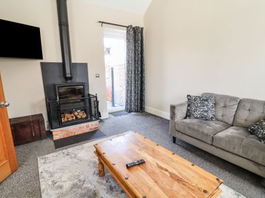 A living room with a fireplace and sofa at Elwy Cottage in St Asaph