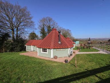 A cottage with a red roof in a grassy area at Antlers Lodge in Biddulph Moor