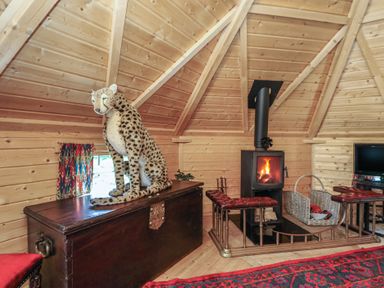 A living room featuring a wood stove and a stuffed leopard at Antlers Lodge in Biddulph Moor