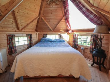 A bedroom with a bed and windows at Antlers Lodge in Biddulph Moor