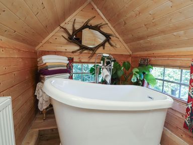 A bathroom with a bathtub and towels at Antlers Lodge in Biddulph Moor