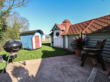 A garden with a barbecue grill and small structures at Antlers Lodge in Biddulph Moor