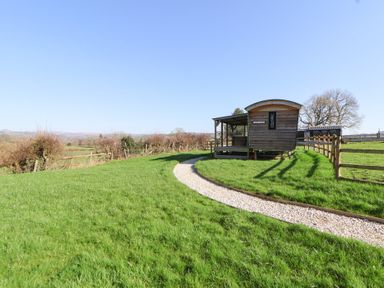 A wooden cabin with a gravel path in a grassy area at Golden Fleece in Biddulph Moor
