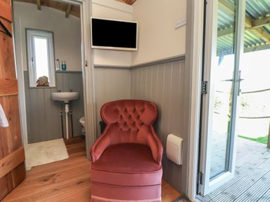 A bathroom with a chair, sink, and television at Golden Fleece in Biddulph Moor