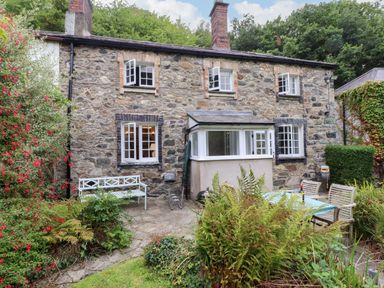 A stone house with a garden table and chairs at 3 Tre Felin in Llandygai near Bangor