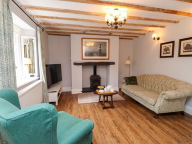 A living room with a sofa, armchair, and television at 3 Tre Felin in Llandygai near Bangor