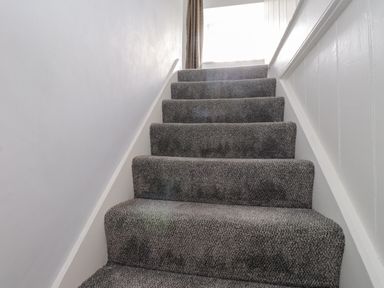 A staircase with carpet leading to a window at 3 Tre Felin Llandygai near Bangor