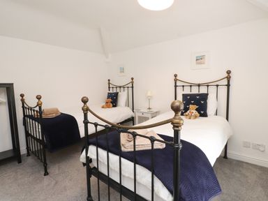 A bedroom with two beds and a nightstand at 3 Tre Felin in Llandygai near Bangor
