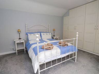 A bedroom with a bed, bedside table, and wardrobe at 3 Tre Felin in Llandygai near Bangor