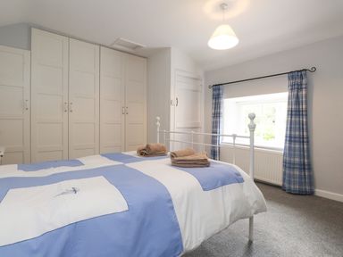 A bedroom with a bed and wardrobe at 3 Tre Felin in Llandygai near Bangor