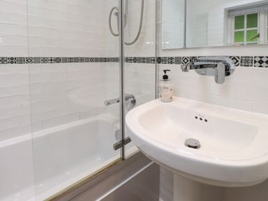 A bathroom with a bathtub, shower, sink and mirror at 3 Tre Felin in Llandygai near Bangor