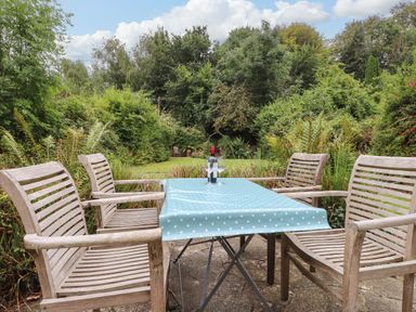A table with chairs and a bottle in a garden at 3 Tre Felin in Llandygai near Bangor