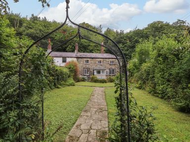 A house with a pathway leading to it surrounded by greenery at 3 Tre Felin in Llandygai near Bangor