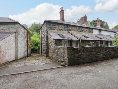 An outdoor view of a stone cottage with a path at 3 Tre Felin in Llandygai near Bangor