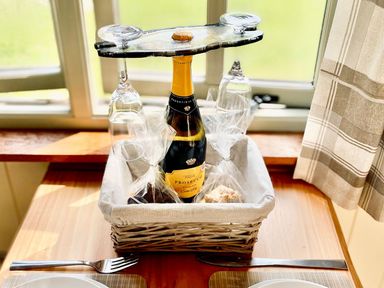 A basket with a wine bottle, glasses and snacks at Cwt Tyddyn Shepherd's Hut in Corwen