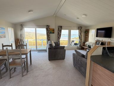 A living room with a sofa and dining table at Wernlas Lodge in Oxwich
