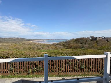 A landscape view of the ocean and hills from a balcony at Wernlas Lodge in Oxwich