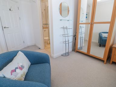 A bedroom with a mirror and a blue sofa at 21 Compass Point in Carbis Bay