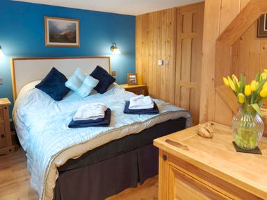 A bedroom with a bed, bedside table, and flowers in a vase at Kaber Chapel near Kirby Stephen