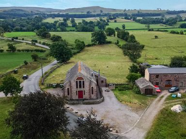 A countryside view with buildings and vehicles at Kaber Chapel near Kirkby Stephen