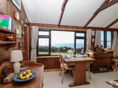A dining room with a table and chairs overlooking the sea at The Cabin
