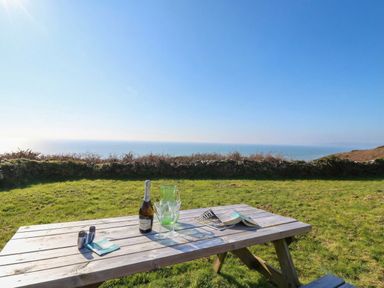 A table with drinks and a magazine overlooking the sea at The Cabin