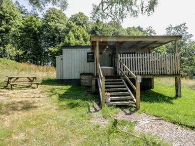 A cabin with a deck and picnic table at Owls Nest Lodge South Molton