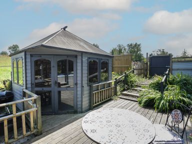 A gazebo with decking and table in the garden at Hedgehogs Lodge South Molton